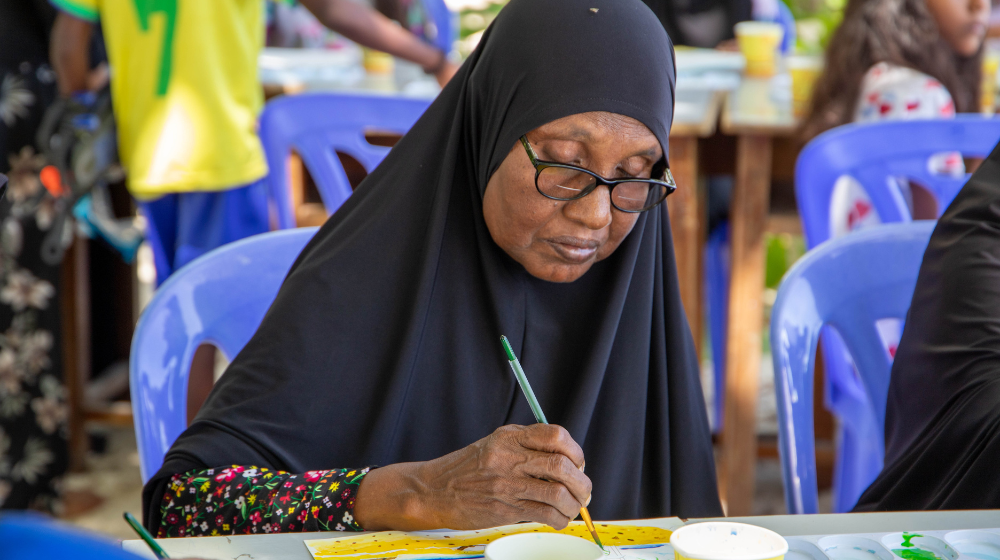 An elderly woman paints.