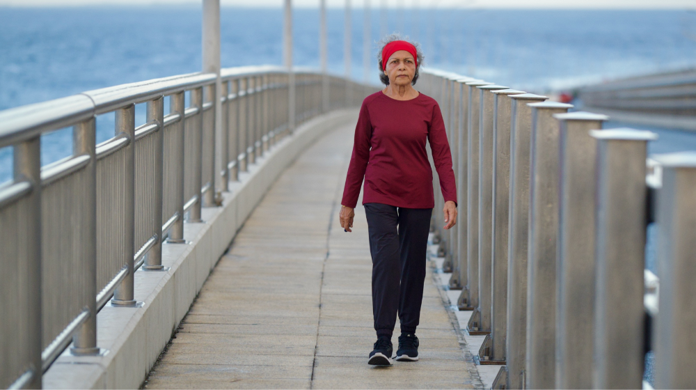 An elderly lady walks across the Sinamale' bridge in the morning.