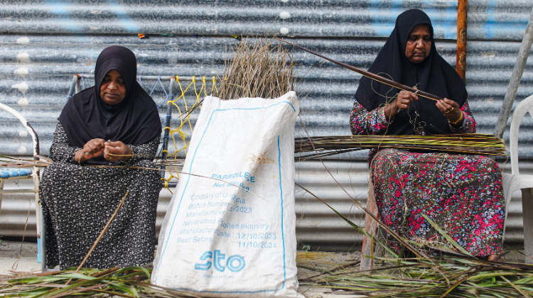 Two elderly woman thatch weaving.