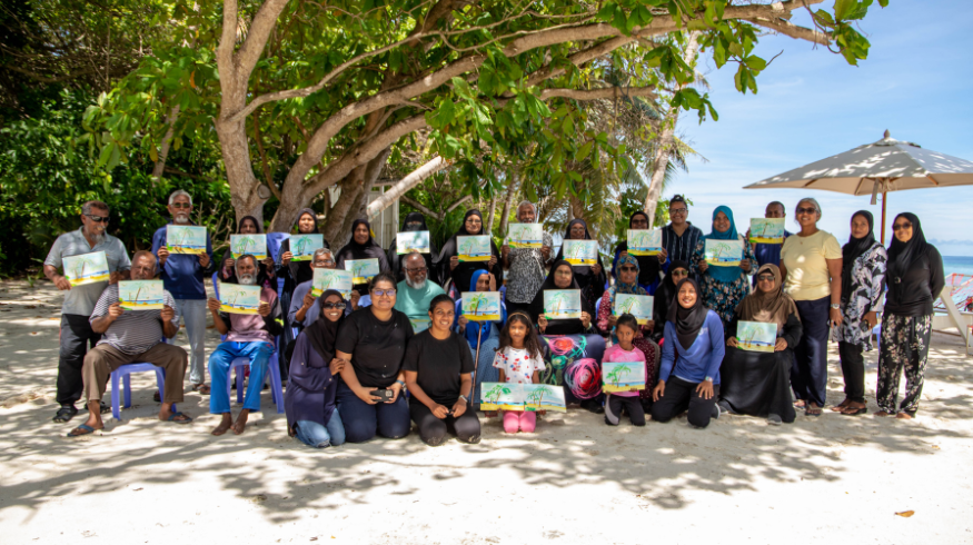 A group of elders holds up their paintings.