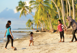 A woman and her three children playing on a beach of Maldives
