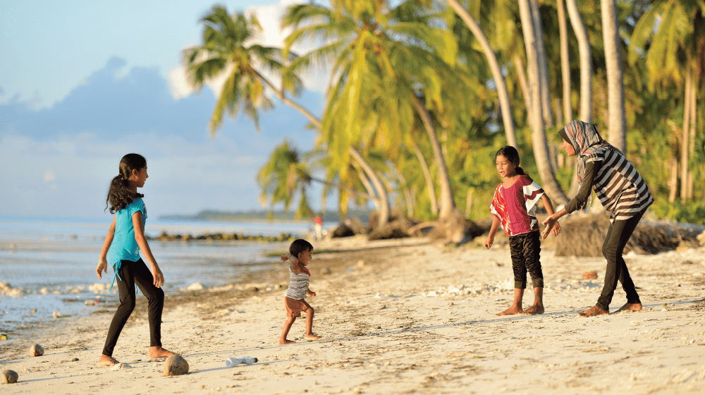 A woman and her three children playing on a beach of Maldives