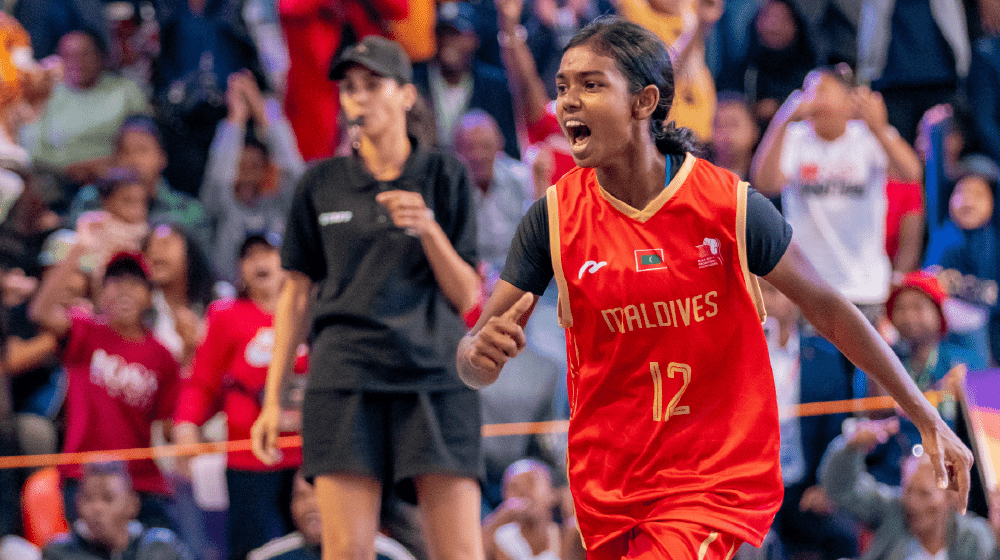 An action shot of a Ifa, wearing a vibrant red Maldives jersey with the number 12, energetically celebrating during a game.