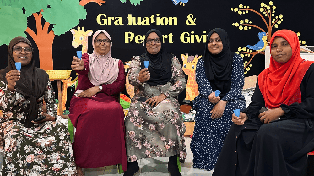 A group of ladies from the session at B. Kudarikilu holding up menstrual cups while posing for the picture