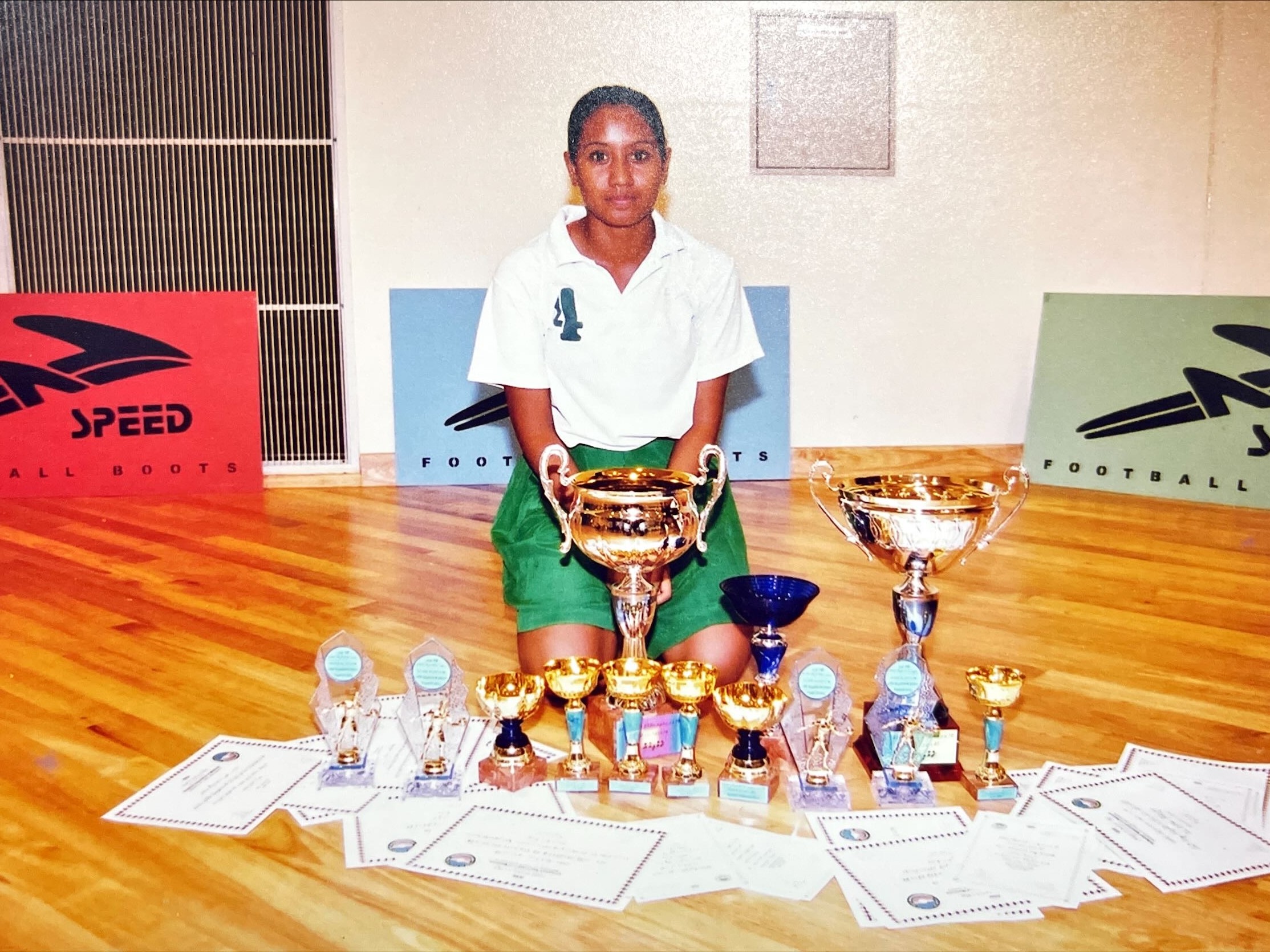Muna, 16, poses for a picture with a trove of medals and trophies from the inter-school volleyball tournament. © Muna
